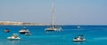 Blue lagoon in Cyprus in the Ayia Napa district next to the Mediterranean sea with pleasure boats and people on the rocks.