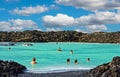 People relaxing in natural beautiful pool with lava stone rocks of thermal outdoor bath, blue turquoise water Royalty Free Stock Photo