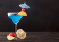 Blue lagoon summer cocktail in margarita glass with sweet cocktail cherries and orange slice with umbrella on dark background Royalty Free Stock Photo