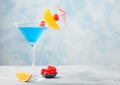 Blue lagoon summer cocktail in martini glass with sweet cocktail cherries and orange slice with umbrella on blue background Royalty Free Stock Photo