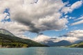 Blue lake amid mountain range and dramatic sky in idyllic uncontaminated environment once covered by glaciers. Dramatic sky