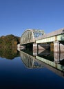 Blue lake with a bridge and autumn trees reflected on the water against a blue sky Royalty Free Stock Photo