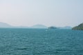 A blue lake in a hazy cloudy day with a boat moving far away