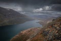 Blue lake with rainbow in mountain landscape from above the hike to Knutshoe summit in Jotunheimen National Park in Norway