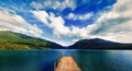 Blue lake with wooden pier surrounded with mountains in New Zealand Royalty Free Stock Photo