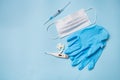 Blue latex gloves on a blue background lie with pills, medical mask, thermometer and syringe Royalty Free Stock Photo