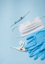 Blue latex gloves on a blue background lie with pills, medical mask, thermometer and syringe. The concept of health and self- Royalty Free Stock Photo