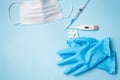 Blue latex gloves on a blue background lie with pills, medical mask, thermometer and syringe Royalty Free Stock Photo