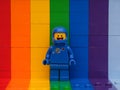 A Blue Lego astronaut Benny minifigure standing against a rainbow backdrop