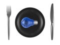 Blue light bulb with sky reflection in it, black plate, steel fork and knife. Top view Royalty Free Stock Photo