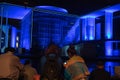 Blue light effects of buildings beyond tourists in foreground sitting looking across in Government District Berlin