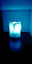 Blue light electric flameless battery powered candle shining in dark cabinet