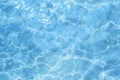 Blue, light pool water outside. Water texture on a sunny day, top view. Ripples and glare on the swimming pool surface. Royalty Free Stock Photo