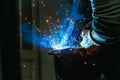 Blue light of welding work with sparks and smoke. Welding shop worker in protective gloves Royalty Free Stock Photo
