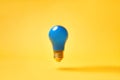 Blue lightbulb levitate on yellow background. Idea and inspiration concept