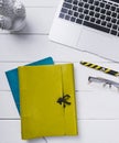 Blue and lime leather book, a pen, glasses and an open notebook on a white background of vintage wooden planks vertical top view Royalty Free Stock Photo