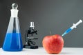 Blue liquid, apple, syringe and microscope on a laboratory table