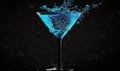 a blue liquid splashing into a martini glass on a black background Royalty Free Stock Photo