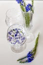 Blue little flowers float in the water, inside crystal glasses.