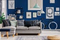 Blue living room with inspiring poster on the wall and grey sofa