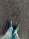 blue loafers with blue jeans on a grey road.