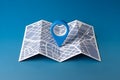 Blue location pin on folded map, simplified city layout, solid blue background, locational theme Royalty Free Stock Photo