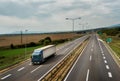 Blue lorry truck driving on asphalt highway road in a pastoral landscape