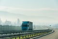 Blue lorry truck driving on asphalt highway road in a rural landscape