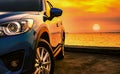 Blue luxury SUV car parked on concrete road by sea beach with beautiful red sunset sky. Summer vacation at tropical beach. Road Royalty Free Stock Photo