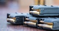 Magazines with bullets of firearm putted on wooden table. Close up view, blurred background. Royalty Free Stock Photo