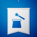 Blue Magic hat and wand icon isolated on blue background. Magic trick. Mystery entertainment concept. White pennant Royalty Free Stock Photo