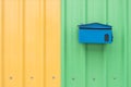 Blue mail box on orange and green corrugated metal sheet as back