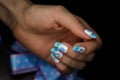 Blue manicure with a flower pattern, and a bow in hand Royalty Free Stock Photo