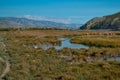 Blue marsh river flows among yellow grass with a stone bank in the Baikal mountains. Autumn sunny landscape. Royalty Free Stock Photo