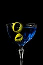 Blue martini cocktail with lemon peel on a black background Royalty Free Stock Photo
