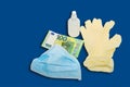 The blue mask lies in yellow protective medical gloves with an antiseptic and money 100 hundred euros. The concept of buying items Royalty Free Stock Photo