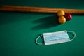 Blue medical face mask for Coronavirus on a green billiard table, protective medical mask for Covid-19 on pool,snooker table