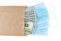 Blue medical face masks and stack of 100 USD banknotes in brown paper packet isolated on white background Royalty Free Stock Photo