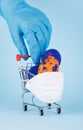 Blue medical gloved hand pull a grocery cart in protective mask with easter eggs. Easter time in quarantine, Easter holyday and Royalty Free Stock Photo