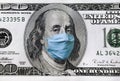 Blue medical mask on the face of Benjamin Franklin with a hundred dollar bill. The concept of the global economic crisis