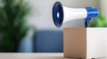 Blue Megaphone on Cardboard Box with Blurred Background Royalty Free Stock Photo