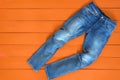 Blue mens jeans denim pants on orange background. Contrast saturated color. Fashion clothing concept. View from above