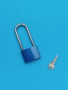 Blue metal lock with a small key on a blue background Royalty Free Stock Photo