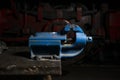 Blue metal mechanical vise mounted on a workbench in the repair shop