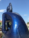 A blue metal and modern statue of a girl sitting and waiting