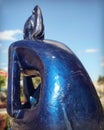 A blue metal and modern statue of a girl sitting and waiting