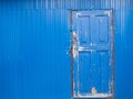 Blue metal wall and blue old door closed with a padlock Royalty Free Stock Photo