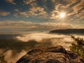 Blue misty daybreak. Sandstone cliff above deep foggy valley in mountains.