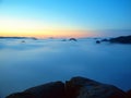 Blue misty morning, view over rock to deep valley full of light mist. Dreamy spring landscape within daybreak