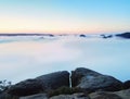 Blue misty morning, view over rock to deep valley full of light mist. Dreamy spring landscape within daybreak